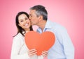 Mature man kissing woman holding a heart Royalty Free Stock Photo