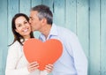 Mature man kissing a woman holding red heart Royalty Free Stock Photo