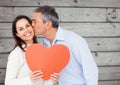 Mature man kissing a woman holding red heart Royalty Free Stock Photo