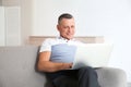 Mature man with laptop sitting on sofa Royalty Free Stock Photo