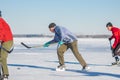 Mature man leading pack while playing hockey with friends on a frozen river Dnipro in Ukraine