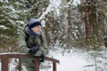 Mature man leaning on wooden railing in snowy winter forest Royalty Free Stock Photo