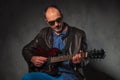 Mature man in leather jacket playing guitar Royalty Free Stock Photo