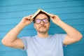 Mature man lifting up his eyes and holding book on his head. Funny person fooling around