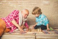 Mature man with little boy playing chess. Checkmate. Cute little boy playing chess. Childhood. Grandfather and grandson
