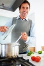 Mature man looking away while cooking in kitchen. Portrait of a happy mature man looking away while cooking in kitchen. Royalty Free Stock Photo