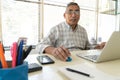 Mature man looking at camera sitting in front of laptop computer