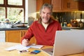 Mature Man Looking At Home Finances In Kitchen