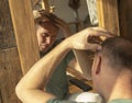 Mature man looking at mirror reflection and is sad with alopecia and hair loss Royalty Free Stock Photo