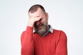 Mature man making facepalm gesture, covering eyes.