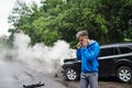 Mature man making a phone call after a car accident, smoke in the background. Royalty Free Stock Photo