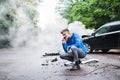 Mature man making a phone call after a car accident, smoke in the background. Royalty Free Stock Photo