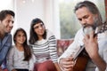 Mature man, music and playing guitar for family at home, relaxing and enjoying together on sofa. Performance, parents Royalty Free Stock Photo