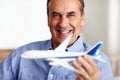 Mature man, portrait and toy plane for travel, vacation and holiday planning with a smile at home. Happy, airplane model