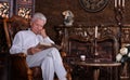 Mature man reading book at room with vintage interior Royalty Free Stock Photo