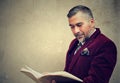 Mature man reading an old book standing by a concrete wall outdoors Royalty Free Stock Photo