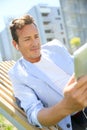 Mature man relaxing in park using tablet Royalty Free Stock Photo