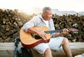 . Mature man, relaxing and playing the guitar while sitting outdoors and enjoying his hobby while getting fresh air Royalty Free Stock Photo