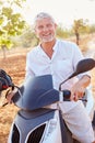 Mature Man Riding Motor Scooter Along Country Road Royalty Free Stock Photo