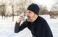 mature man running at winter in park have some breathing difficulties and using asthma pump