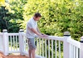 Mature man sanding railing of outdoor natural cedar deck