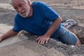 Mature man or senior walking in a building zone and falling in a big hole with her leg inside it - needing help on the ground with