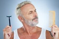 Mature man, shaver and comb thinking for grooming, skincare or hair removal against studio background. thoughtful senior Royalty Free Stock Photo