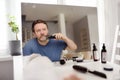Mature man is shaving off his beard with electric razor at home during quarantine. Handsome bearded man trimming his beard with Royalty Free Stock Photo