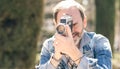 Mature man shooting video in city park with vintage camera Royalty Free Stock Photo