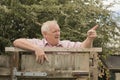 Mature man shouting over a fence in the garden