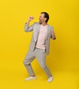 Mature man singing holding invisible microphone laughing wearing white casual suit isolated on yellow background Royalty Free Stock Photo