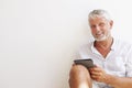 Mature Man Sitting Against Wall Using Digital Tablet Royalty Free Stock Photo