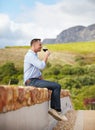 Enjoying some wine in the great outdoors. A mature man sitting on wall and enjoying a glass of red wine. Royalty Free Stock Photo