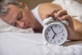 Mature man sleeping in bed with alarm clock in foreground at bed Royalty Free Stock Photo