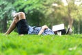 Mature man sleeping on green grass in city park with a book cov