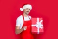 mature man smile in santa hat and red apron hold present Royalty Free Stock Photo