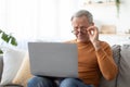 Mature man squinting using laptop, looking at screen