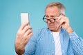 Mature man squinting using mobile phone, looking at screen Royalty Free Stock Photo