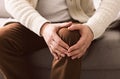 Mature man suffering from knee pain on sofa Royalty Free Stock Photo