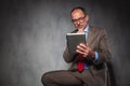 Mature man in suit thinking and using his tablet