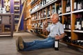 Mature man tasting red wine sitting on floor Royalty Free Stock Photo