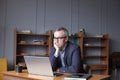 Mature man thinking, planning and using laptop in office or co-working space Royalty Free Stock Photo