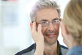 Mature man trying on eyeglasses with optician