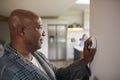 Mature Man Turning Control Dial On Digital Central Heating Thermostat At Home Royalty Free Stock Photo