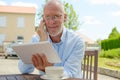 Mature man use tablet . Sitting in the garden Royalty Free Stock Photo