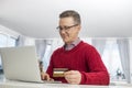 Mature man using credit card and laptop to shop online during Christmas Royalty Free Stock Photo