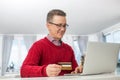 Mature man using credit card and laptop to shop online during Christmas Royalty Free Stock Photo