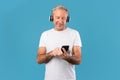 Mature man using his mobile phone wearing wireless earphones Royalty Free Stock Photo