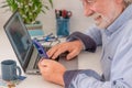 Mature man using laptop computer and mobile phone at home, Businessman working in office.Freelance, studying, technology online Royalty Free Stock Photo