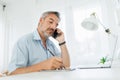 Mature man using mobile phone while writing something on digital tablet Royalty Free Stock Photo